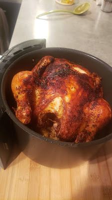 a cooked chicken in a pan sitting on a counter top next to a digital camera