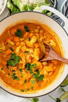 a large pot filled with soup and garnished with cilantro, cauliflower and parsley