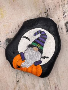 a painted rock with a gnome holding a pumpkin