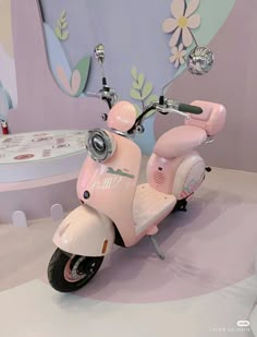 a pink scooter is on display in a showroom with flowers painted on the walls