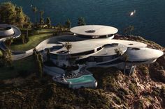 an aerial view of a futuristic house on top of a hill next to the ocean