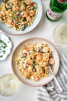 two plates of pasta with shrimp and spinach