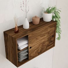 a wooden shelf with two vases and towels on it next to a potted plant