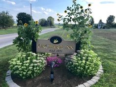 the sign for orchard inn is surrounded by sunflowers and other flowers in bloom