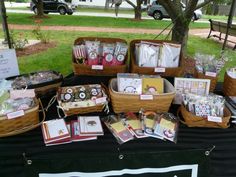 the table is covered with cards and other items for sale at an outdoor market stall