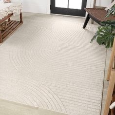 a large white rug in the middle of a room next to a wooden bench and window