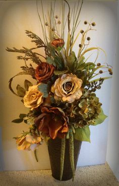 a vase filled with lots of flowers on top of a floor next to a wall