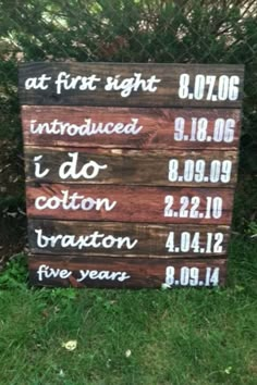 a wooden sign sitting on top of a lush green field