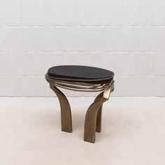 a black and gold stool sitting on top of a white floor next to a wall