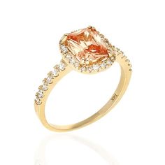 a yellow gold ring with an orange and white diamond in the center, on a white background