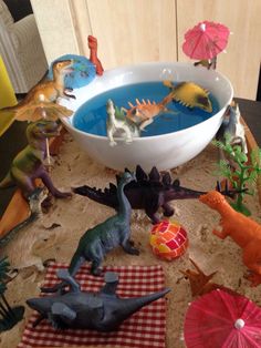 toy dinosaurs and other toys in a bowl on a table