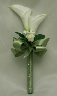 a boutonniere with white flowers and green leaves on it's side