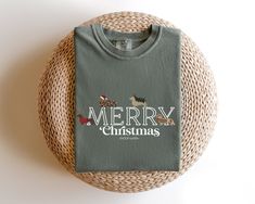 a t - shirt that says merry christmas on it sitting next to a wicker basket