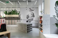 the interior of a clothing store with plants on shelves