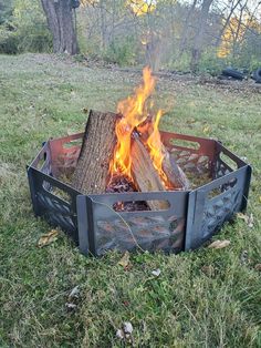 a fire pit sitting on top of a lush green field next to a tree stump