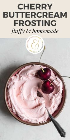 a bowl filled with pink whipped cream and two cherries on top of the bowl