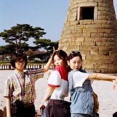 three girls standing next to each other in front of a tower