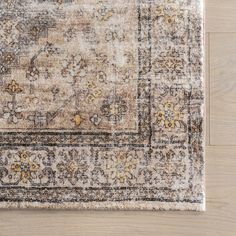 an area rug with beige and brown colors on top of a wooden floor next to a white wall