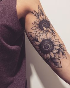 a woman's arm with two sunflowers tattooed on the left side of her arm