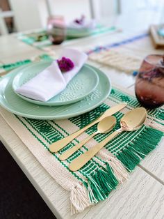 a place setting with green plates and gold utensils