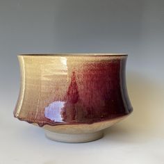 a brown and red bowl sitting on top of a white table next to a wall