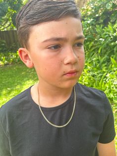 a young boy wearing a black shirt and necklace