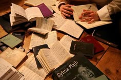 many books are spread out on the floor with one person's hands resting on them