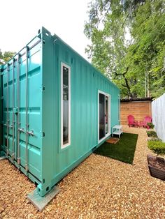 a green shipping container sitting on top of a gravel field