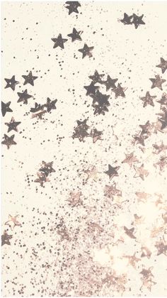 the stars are falling down on the white surface with black dots and glitters in it