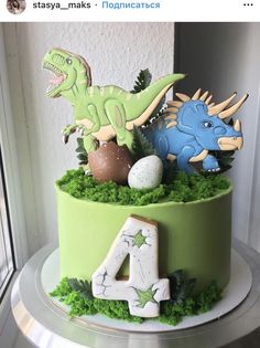 a green cake with dinosaur decorations on top and the number four in front of it