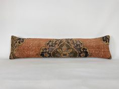 an orange and black decorative pillow on a white surface with a light brown back ground