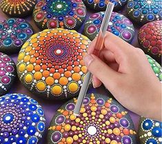 a person is holding a pencil in their hand and painting rocks with dots on them