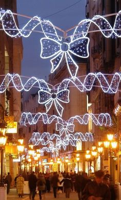 people walking down a city street covered in christmas lights