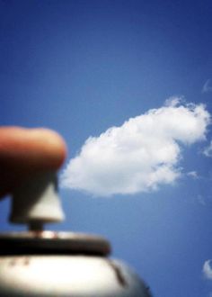 a hand is holding the top of a teapot in front of a blue sky with white clouds