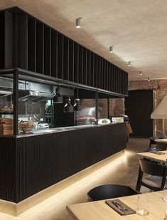 an empty restaurant with tables and chairs in front of the counter, along with lights on