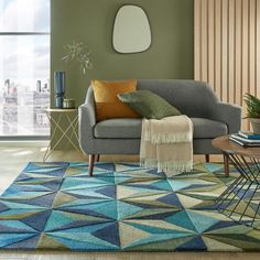 a modern living room with green walls and colorful rugs on the floor in front of a gray couch