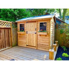 a small wooden shed sitting on top of a wooden deck next to a fence and trees