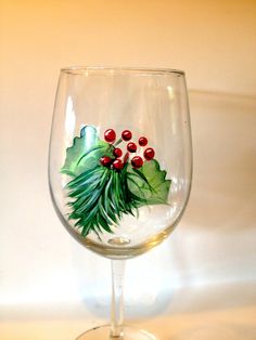 a wine glass with holly and berries painted on it