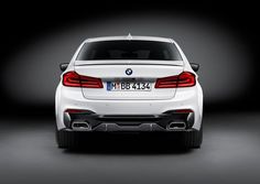 the back end of a white bmw car in a dark room with its lights on