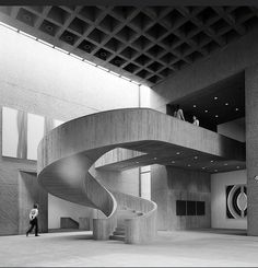 an artistic sculpture in the middle of a building with stairs and people walking around it