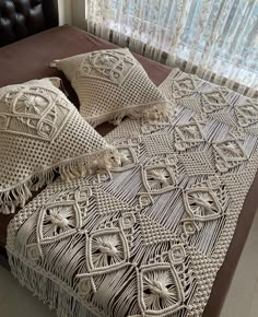 a bed with two pillows on top of it next to a brown headboard and window