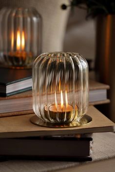 a glass candle holder sitting on top of a wooden table next to a stack of books