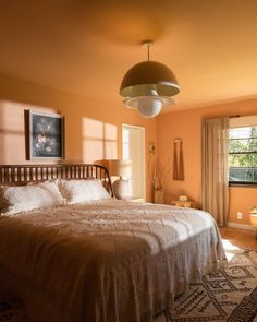 a large bed sitting in a bedroom next to a window with curtains on the windowsill