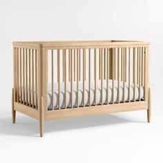 a wooden crib with white sheets on the top and bottom sides, in front of a plain background