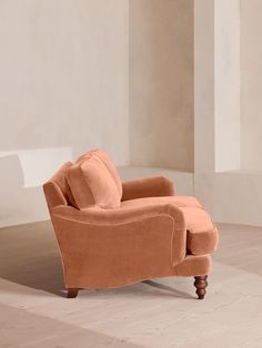 an orange chair sitting on top of a hard wood floor next to a white wall