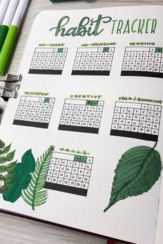 a calendar with green leaves on it next to markers and pencils in front of them