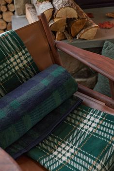 a chair with plaid fabric on it next to firewood logs and wood logs