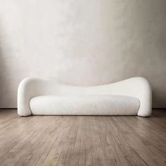 a white couch sitting on top of a hard wood floor next to a wall in an empty room