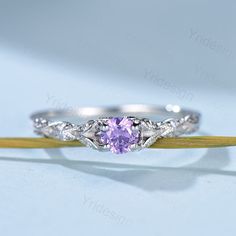 a purple diamond ring sitting on top of a wooden stick