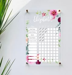 a white and pink flowered planner on top of a table next to a potted plant